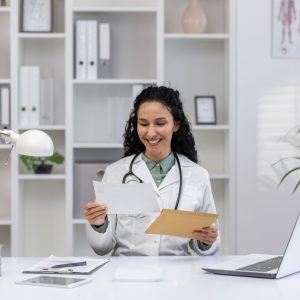 A cheerful Hispanic female doctor, in a white coat, reads an exciting letter or notification in a bright, modern medical office.